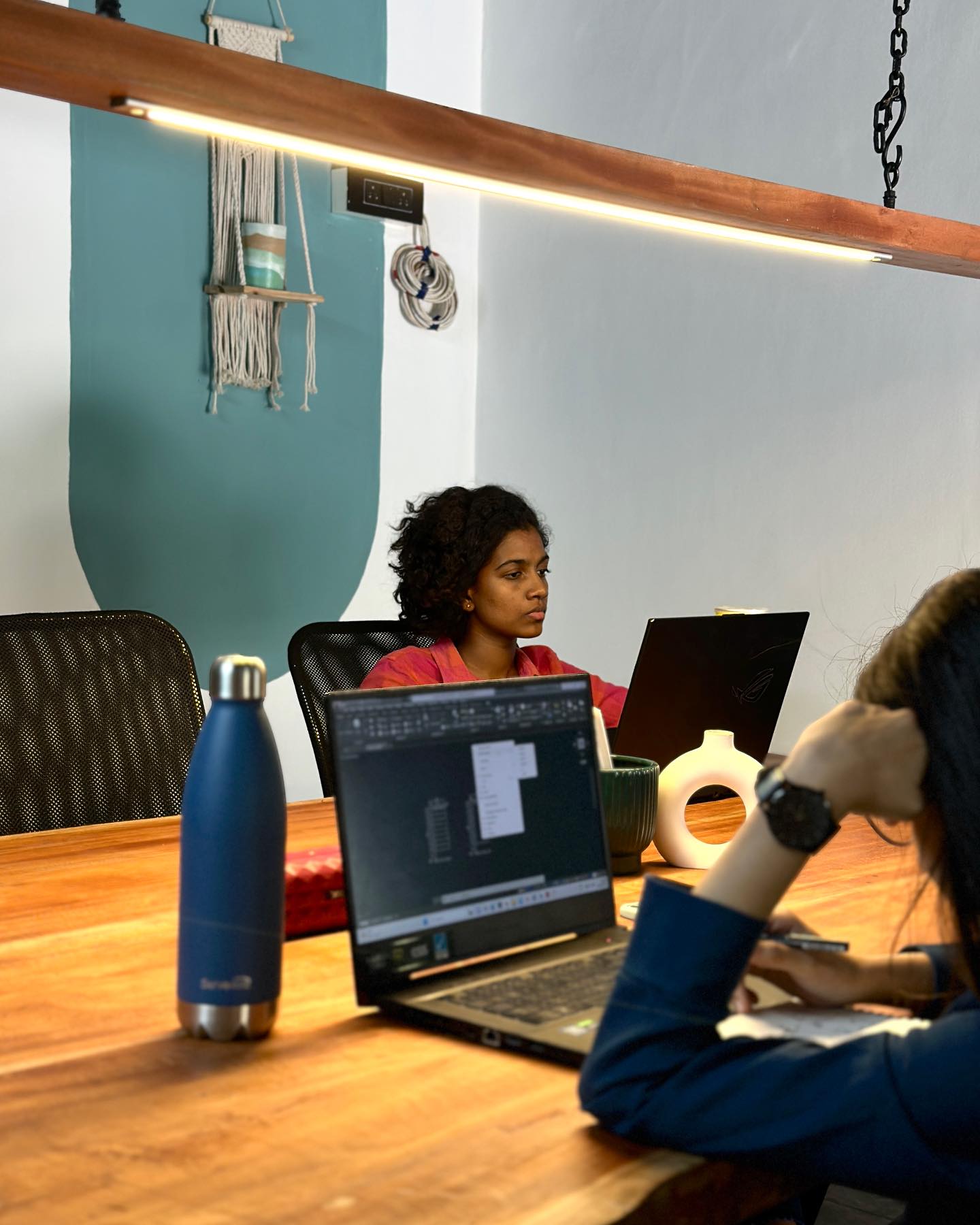 The NHgreen team at the long studio table — CAD drawings open on laptops
