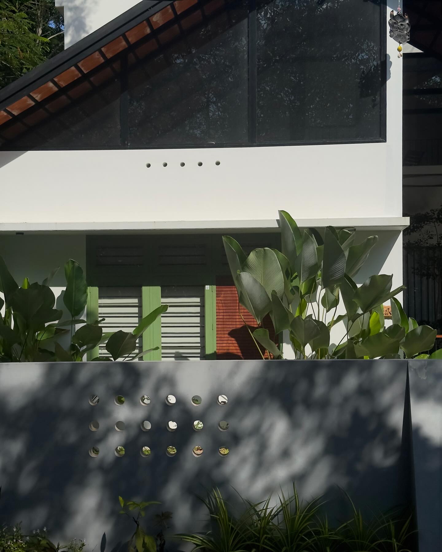 The NHgreen studio in Thirumala — green shutter and bird-of-paradise courtyard